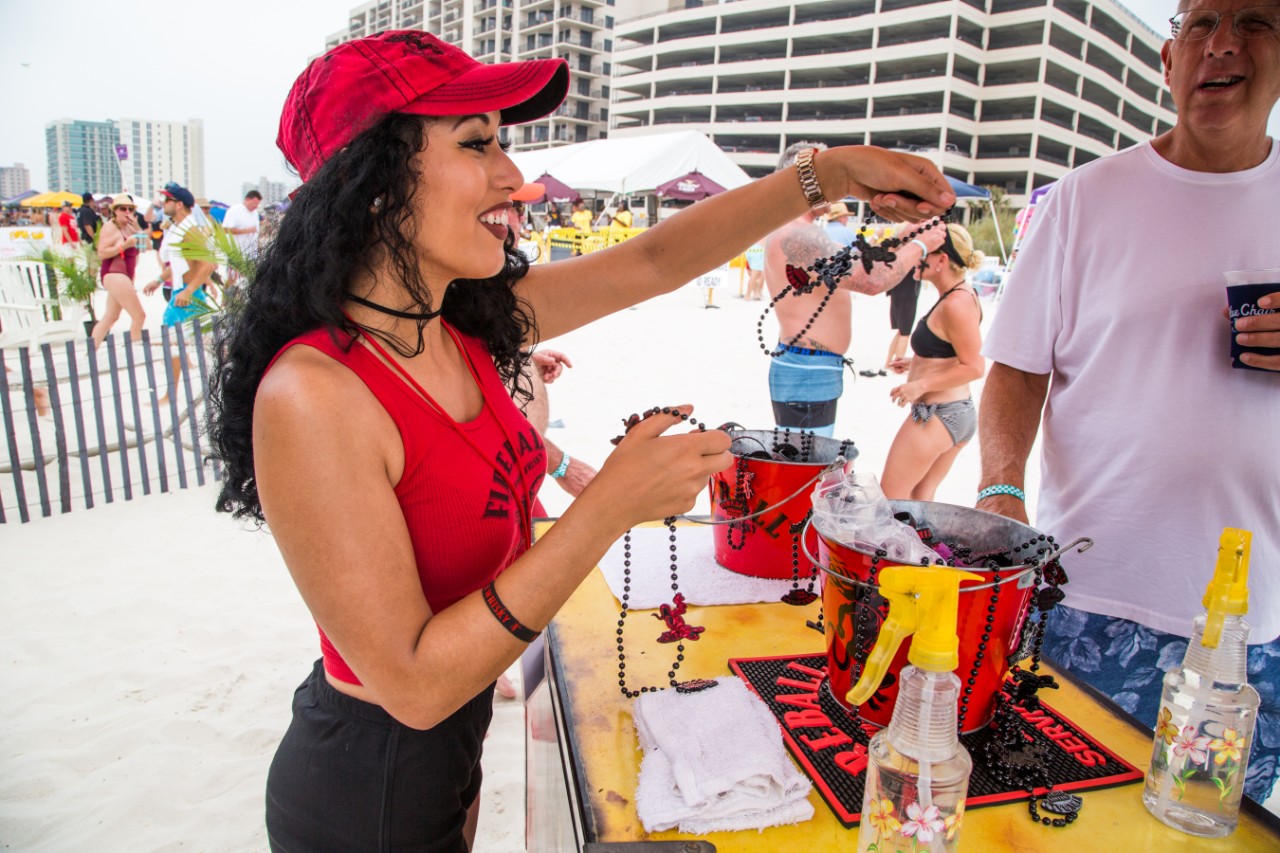 Female bartender handing out Fireball beads on beach